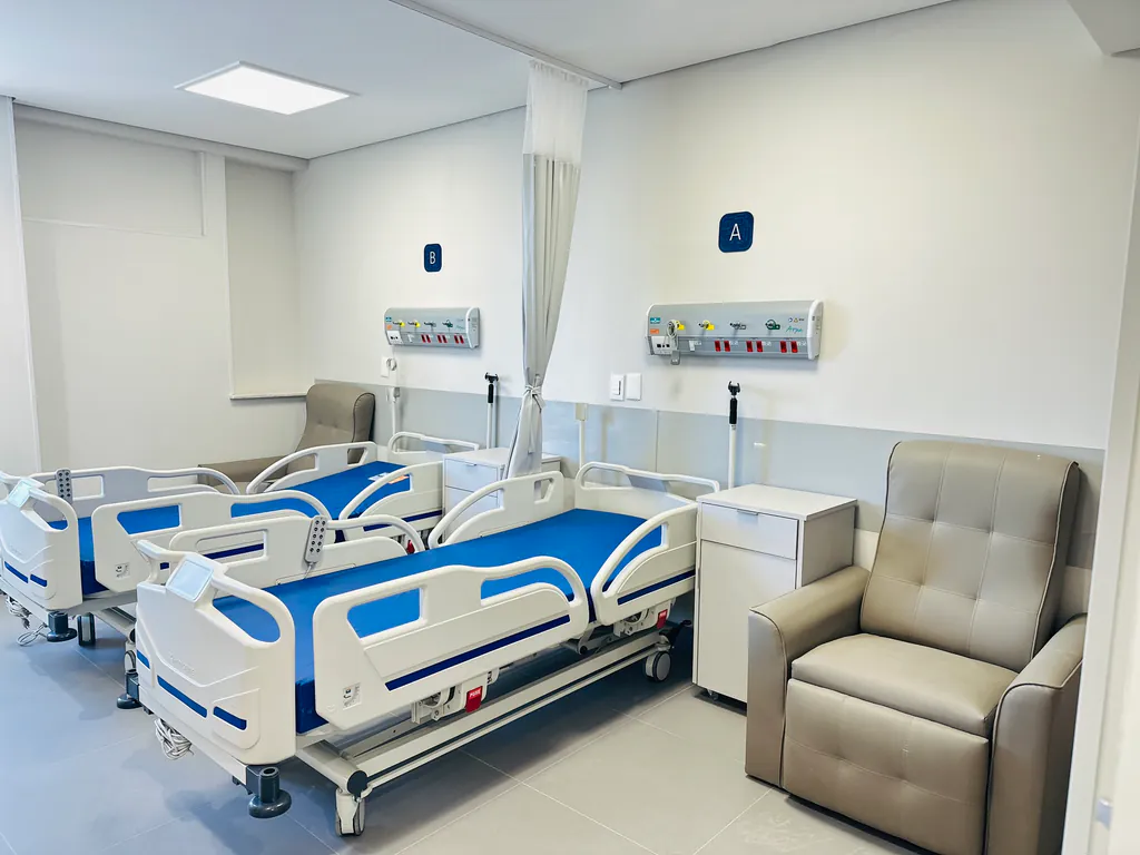 Quarto de internação do Hospital Raja com dois leitos e poltrona para acompanhante